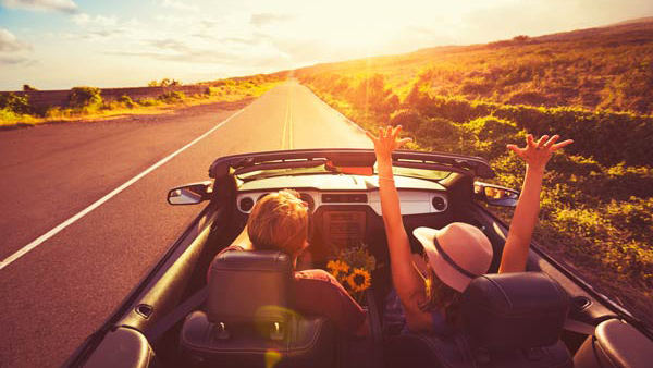 Happy Young Couple Driving Along Country Road in Convertible at